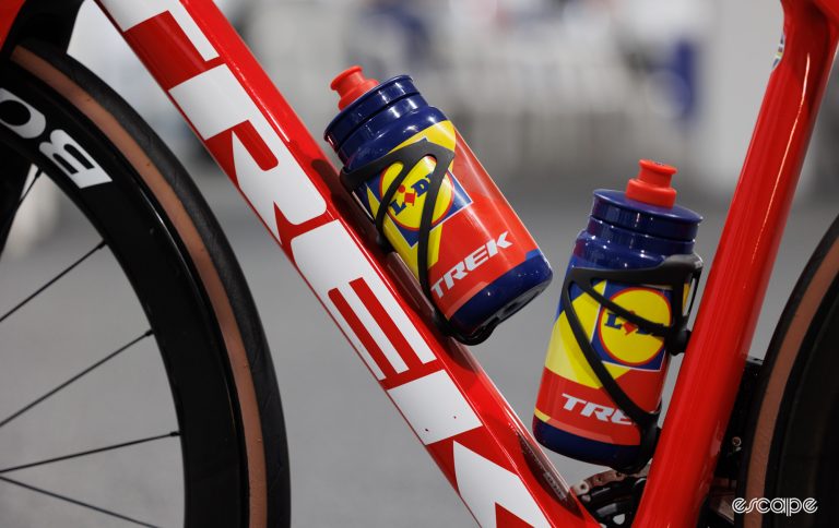 A Trek road bike with Lidl-Trek team water bottles. The close-cropped shot shows the large Trek logo on the down tube, the seat tube, and the bottles, as well as part of the front wheel.